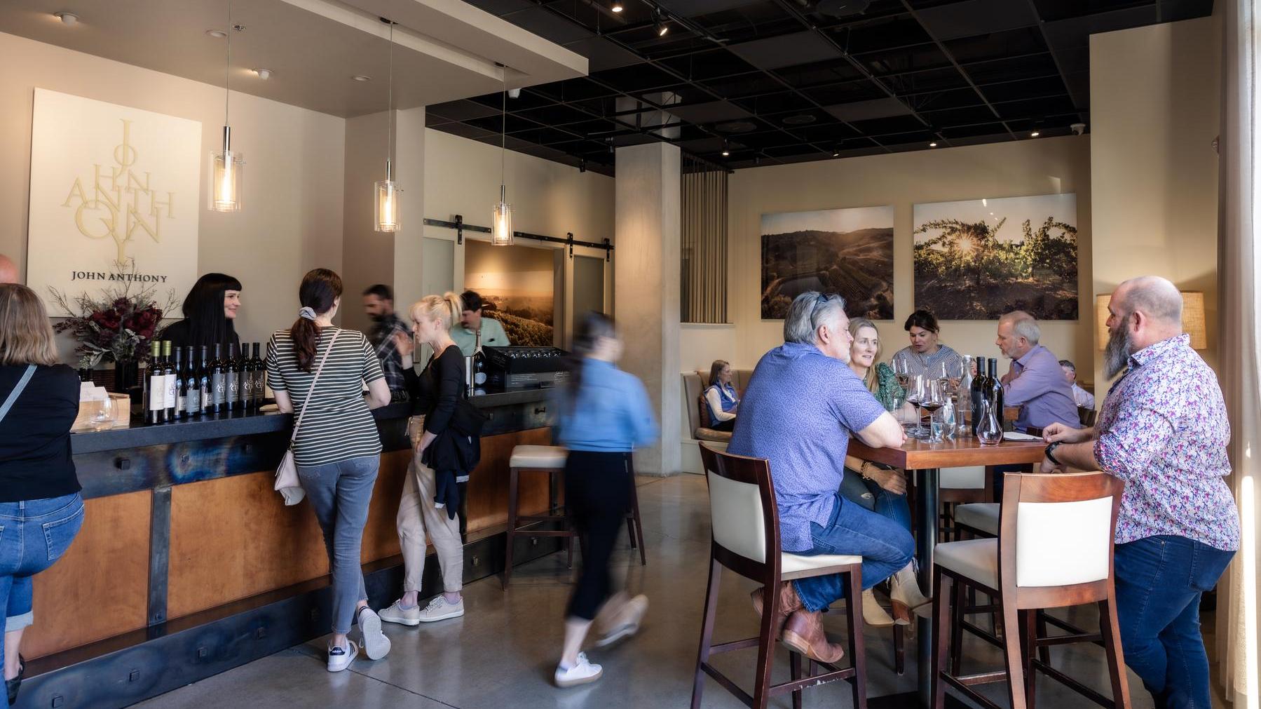 Busy John Anthony tasting lounge during peak season in Napa Valley: Guests enjoy wine, chatter, and hospitality in a warm, inviting space.