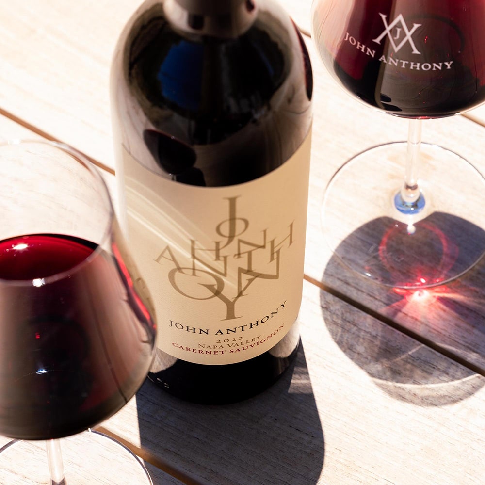 Bottle of JAV wine with wine glasses on a table.